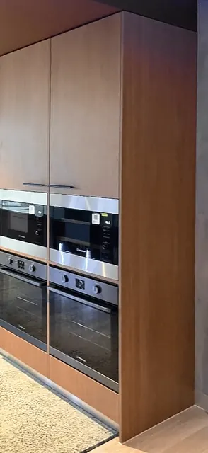 Floor-to-ceiling timber oven tower with two built-in microwaves above two wall ovens and a timber end panel.